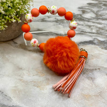 Load image into Gallery viewer, Silicone Bracelet Keychain - Tassel &amp; Pom Pom- Orange &amp; Floral
