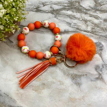 Load image into Gallery viewer, Silicone Bracelet Keychain - Tassel &amp; Pom Pom- Orange &amp; Floral
